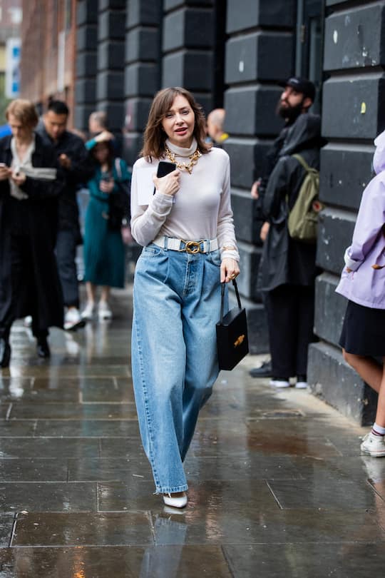 LONDON, ENGLAND - SEPTEMBER 16: A guest is seen wearing high waist wide leg denim jeans with belt, turtleneck, necklace outside Christopher Kane during London Fashion Week September 2019 on September 16, 2019 in London, England. (Photo by Christian Vierig/Getty Images)