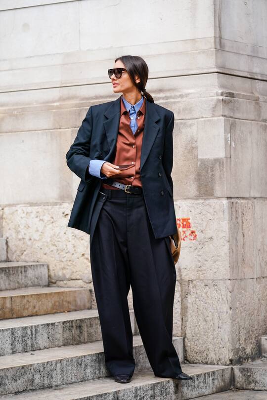PARIS, FRANCE - SEPTEMBER 30: Julie Pelipas wears sunglasses, a blue shirt, a rust-color shirt, a dark grey oversized double-breasted jacket, dark grey oversized wide-legs full-length pants, a black belt, a camel clutch, black shoes, outside Stella McCartney , during Paris Fashion Week - Womenswear Spring Summer 2020, on September 30, 2019 in Paris, France. (Photo by Edward Berthelot/Getty Images)