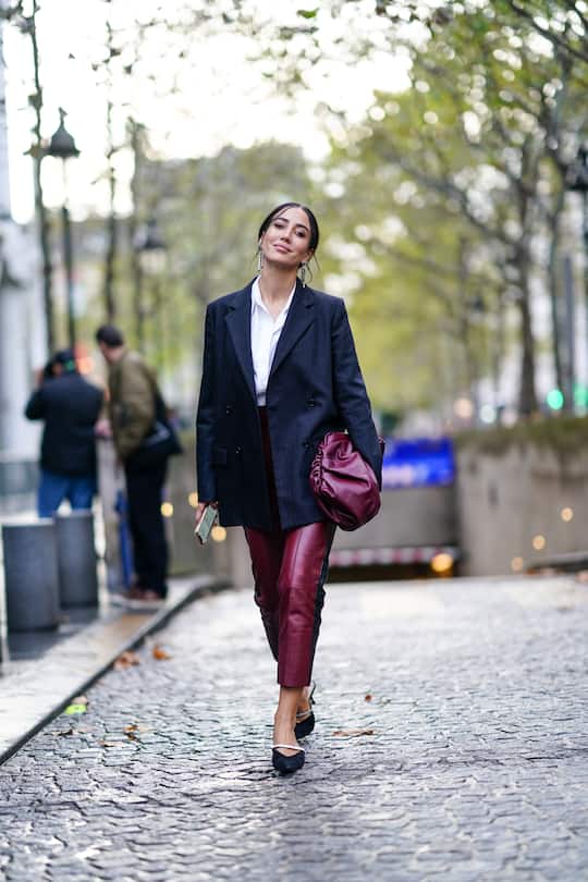 PARIS, FRANCE - SEPTEMBER 24: Tamara Kalinic wears earrings, a white shirt, a navy blue pinstriped jacket, plum-color leather pants, a plum-color puff bag, black suede mules with a rhinestone strap, outside Koche, during Paris Fashion Week - Womenswear Spring Summer 2020, on September 24, 2019 in Paris, France. (Photo by Edward Berthelot/Getty Images)