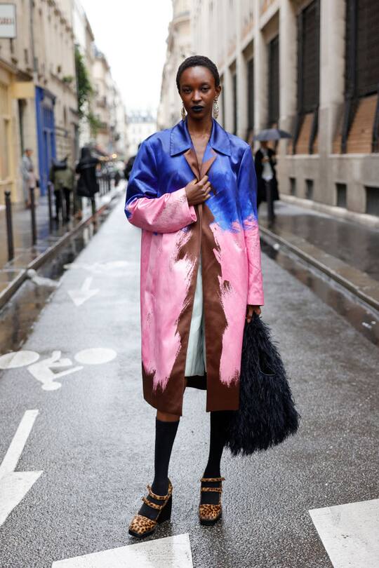 PARIS, FRANCE - SEPTEMBER 25: Nicole Atieno wears blue brown and pink coat, black socks, leopard print heels, black fur bag, outside Dries Van Noten, during Womenswear Spring/Summer 2025 as part of Paris Fashion Week on September 25, 2024 in Paris, France. (Photo by Claudio Lavenia/Getty Images)