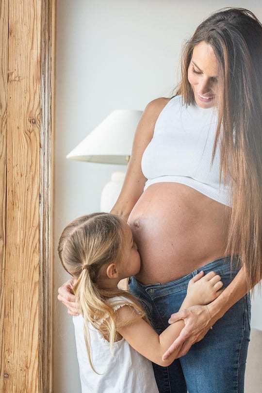 Jennifer Janka mit Ellie, die ihren Schwangerschaftsbauch küsst