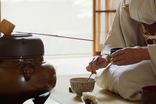 A senior Japanese woman dressed in kimono, acting as the host of a traditional Japanese tea ceremony at a Chashitsu in Tokyo, Japan.