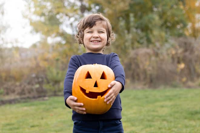 Photo of 4-year smiling boy holding Halloween pumpkin in his hands