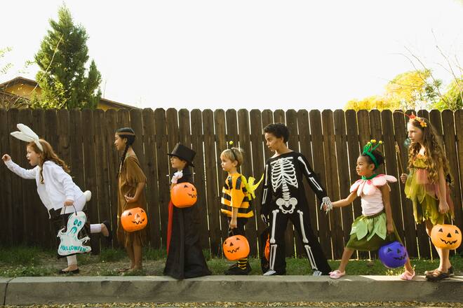 Kinder in Halloween-Kostümen ziehen um die Häuser