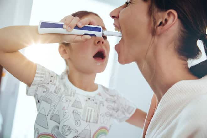 Kind putzt einer erwachsenen Person die Zähne