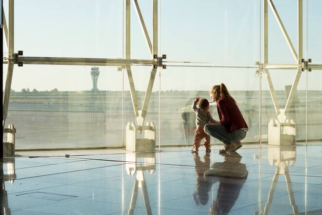 Mother and daughter are looking at planes while waiting to board. It's early in the morning.