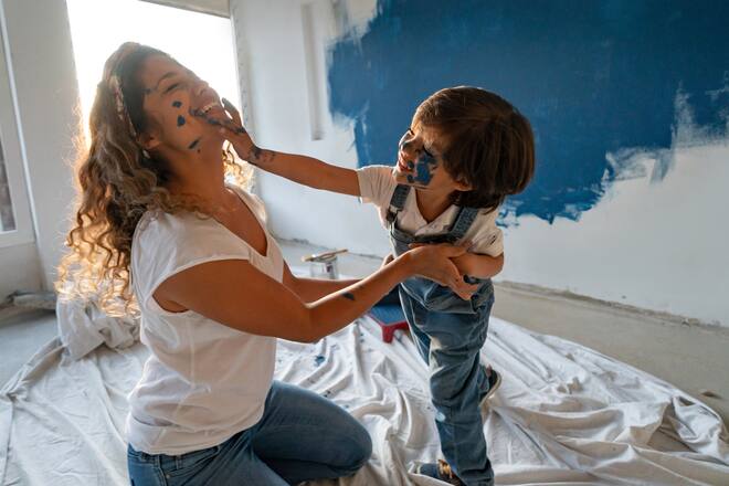 Happy Latin American mother and son painting their house and having fun painting each other - housing project concepts