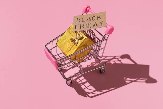 Metal shopping cart with black friday sign and golden gift box with hard shadow, on pink background. Shopping, discounts, opportunities and black friday concept.