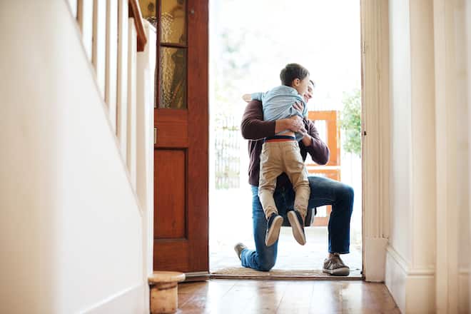 Shot of a little boy running into his father's arms as he arrives at home