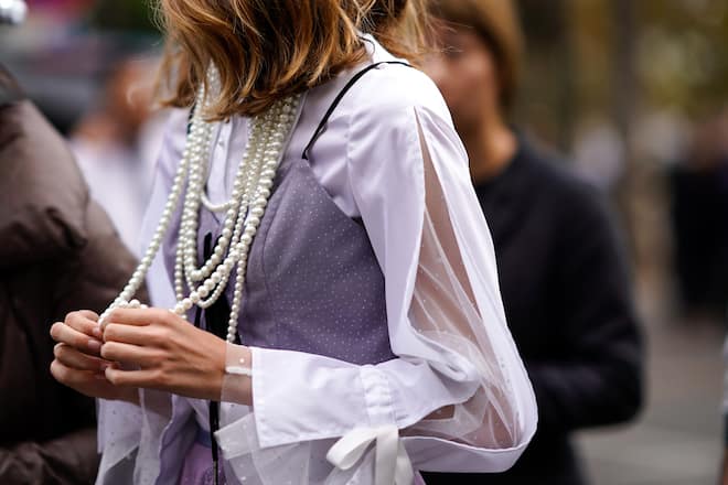 PARIS, FRANCE - SEPTEMBER 30: A guest wears a pearl necklace, a pink lace dress, outside Akris, during Paris Fashion Week Womenswear Spring/Summer 2019, on September 30, 2018 in Paris, France. (Photo by Edward Berthelot/Getty Images)