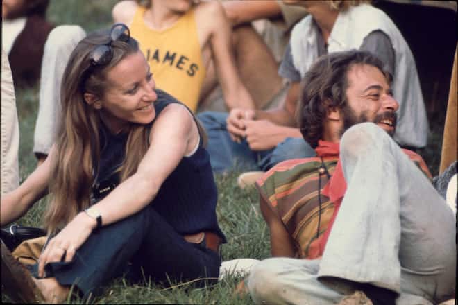 Close-up of a man and woman, who has a camera around her neck, as they sit on the grass in the audience for a performance on the 'Free Stage' at the Woodstock Music and Arts Fair, Bethel, New York, August 1969. The festival ran from August 15 to 18. The 'Free Stage' essentially functioned as both a place from the scheduled performers to jam and as an open mic stage for festival goers. (Photo by Ralph Ackerman/Getty Images)