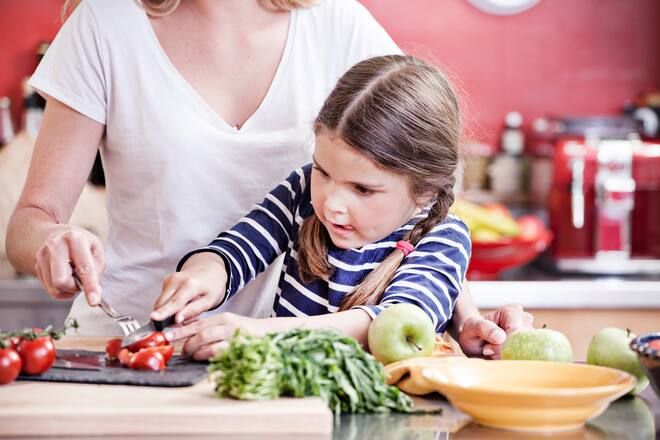 Mädchen rüstet Gemüse mit ihrer Mama