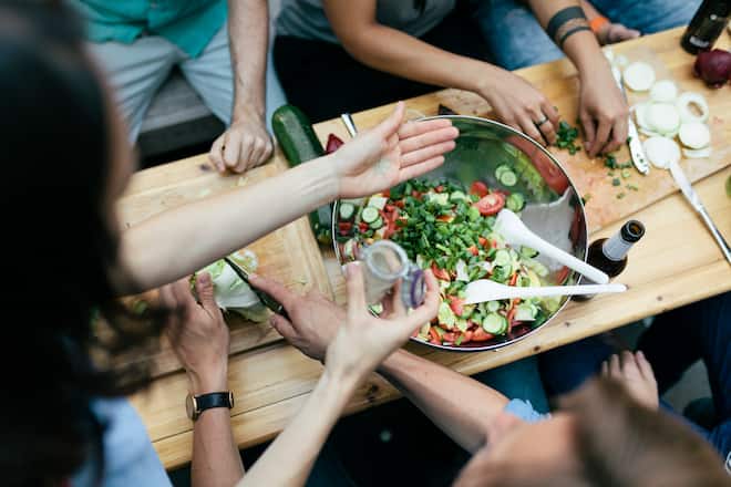A group of friends sat down together preparing food for a barbecue.