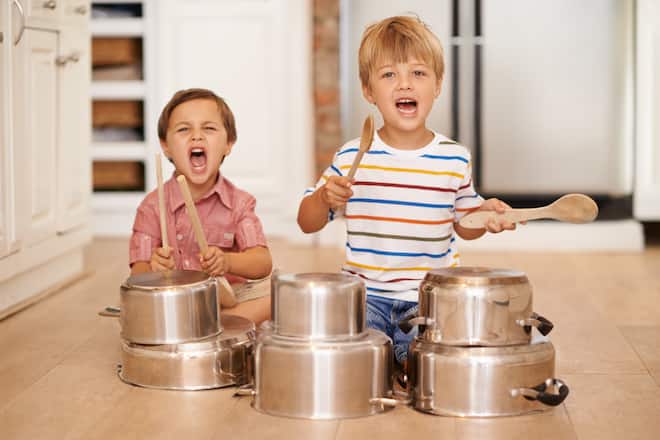 Zwei kleine Jungs spielen in der Küche Schlagzeug auf Töpfen