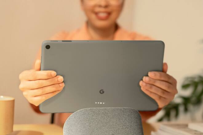 Eine Nutzerin nimmt das Google Pixel Tablet von seinem Ladedock.