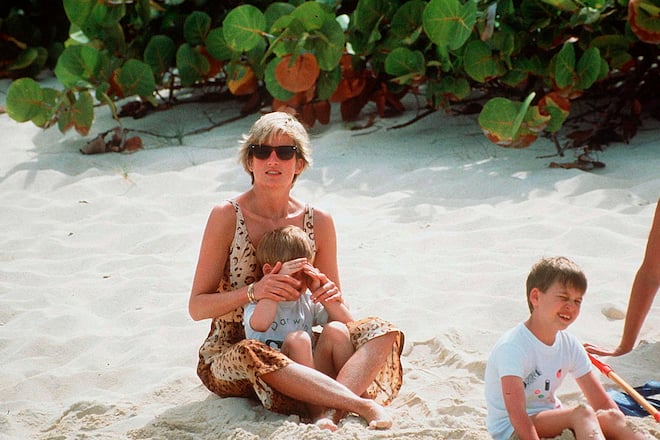 BRITISH VIRGIN ISLANDS - APRIL 11: Diana, Princess Of Wales, Sitting In The Sand With Her Son, Prince Harry, On Her Lap. Prince William Is Sitting Nearby During A Spring Holiday By The Sea. (Photo by Tim Graham Photo Library via Getty Images)